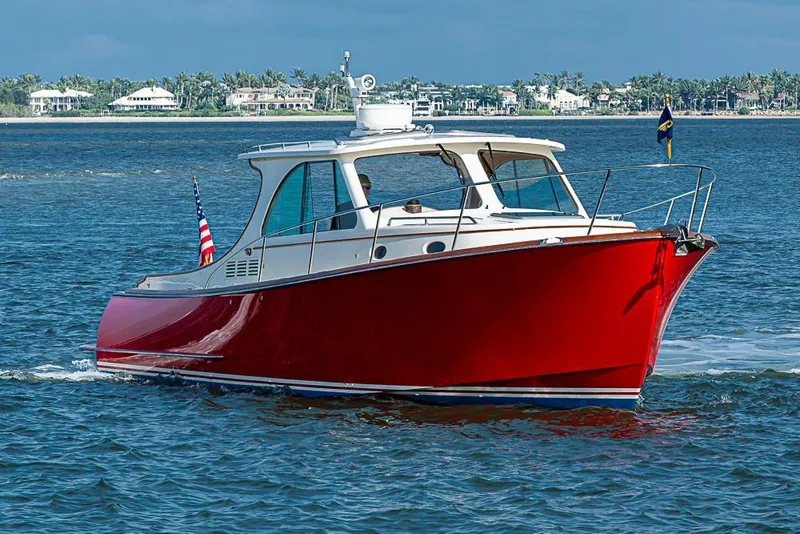 Slide: The Image of 2016 Hinckley Talaria 34 boat with red hull cruising on open water. - 2