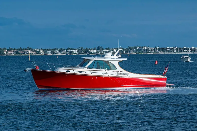 Slide: The Image of 2016 Hinckley Talaria 34 boat cruising on blue water, with coastal background. - 4