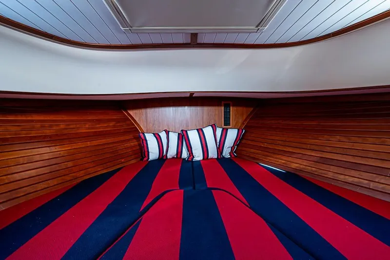 Slide: The Image of Interior cabin of 2016 Hinckley Talaria 34 with striped bedding and wooden paneling. - 13