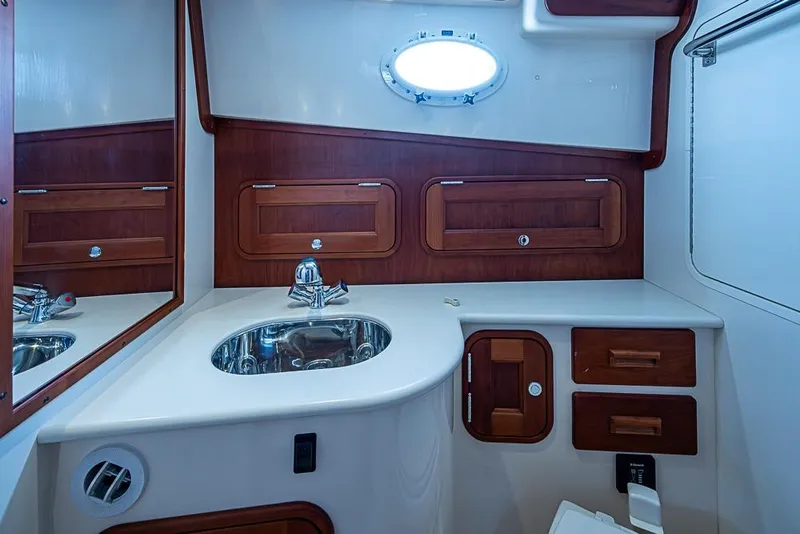 Slide: The Image of 2016 Hinckley Talaria 34 yacht bathroom with wood accents and stainless steel sink. - 15