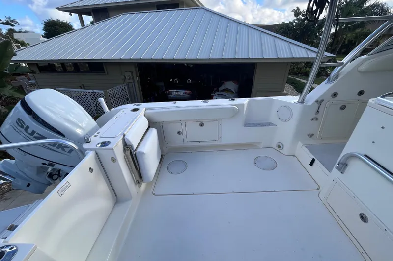 Slide: The Image of 2010 World Cat 290 EC boat deck with Suzuki outboard motor, near a garage. - 14