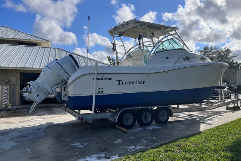 Slide: The Image of 2010 World Cat 290 EC boat on trailer, parked outdoors under a cloudy sky. - 2