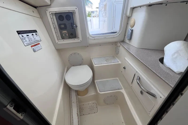 Slide: The Image of Compact bathroom inside 2010 World Cat 290 EC boat, featuring toilet and storage. - 28