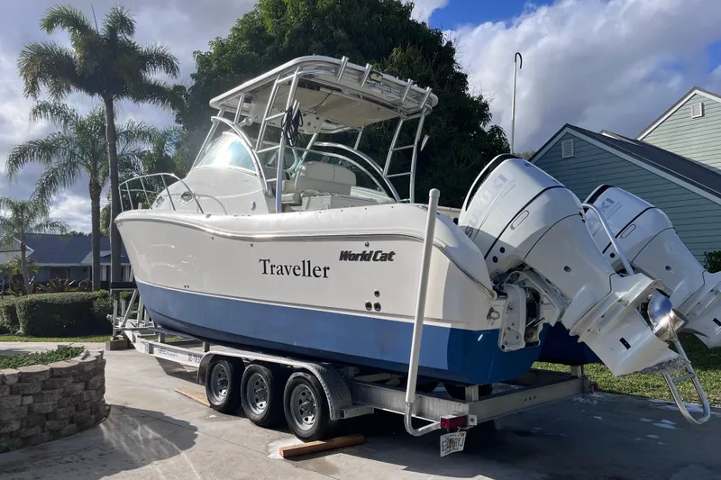Slide: The Image of 2010 World Cat 290 EC boat on trailer, parked outdoors with palm trees. - 4