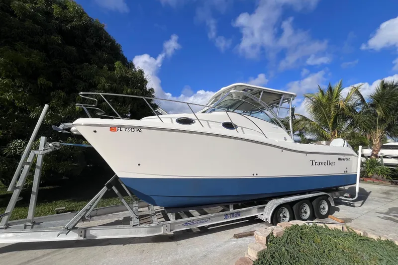 Slide: The Image of 2010 World Cat 290 EC boat on trailer, parked outdoors under blue sky. - 5