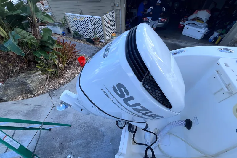 Slide: The Image of Suzuki outboard motor on 2010 World Cat 290 EC boat, parked near garden. - 62