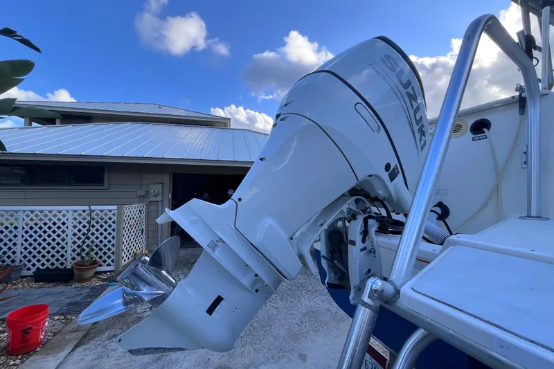 Slide: The Image of 2010 World Cat 290 EC boat with Suzuki outboard motor, parked near a house. - 65