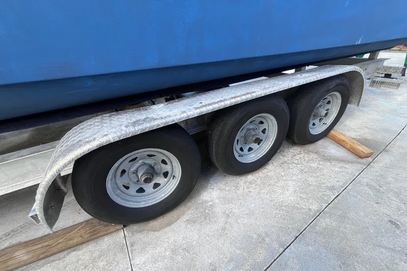 Slide: The Image of Trailer with triple axles for 2010 World Cat 290 EC boat, parked on concrete. - 73