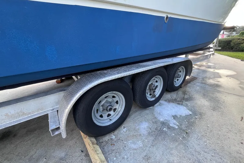 Slide: The Image of 2010 World Cat 290 EC boat on a triple-axle trailer, parked on concrete. - 74