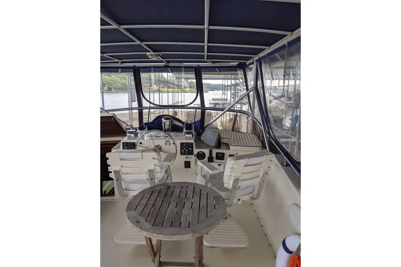 Slide: The Image of 1984 Hatteras 53 Extended Deckhouse Motor Yacht helm with seating and wooden table. - 100