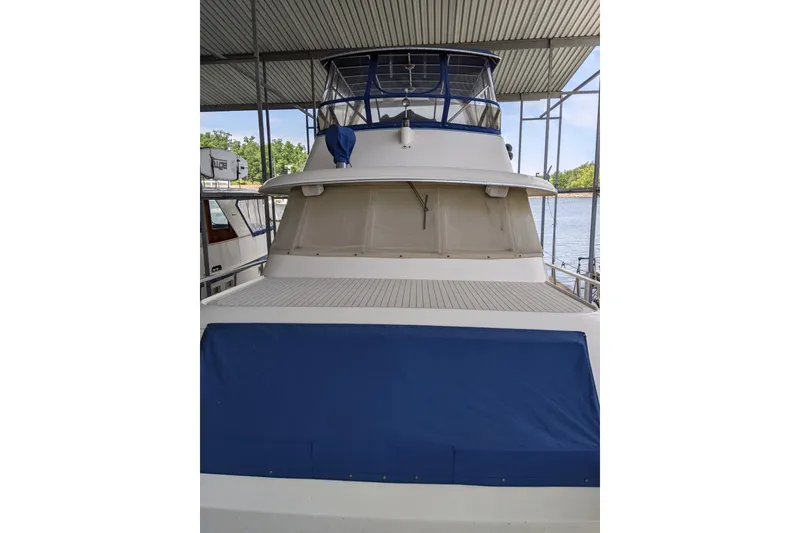 Slide: The Image of 1984 Hatteras 53 Extended Deckhouse Motor Yacht docked under a covered marina. - 101