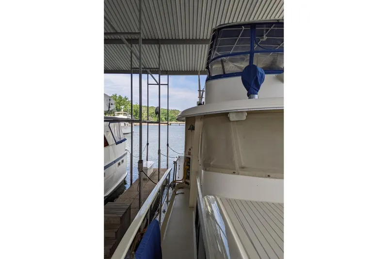 Slide: The Image of 1984 Hatteras 53 Extended Deckhouse Motor Yacht docked under a covered marina. - 102