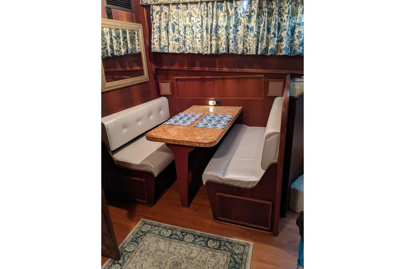 Slide: The Image of 1984 Hatteras 53 Motor Yacht interior with cozy dining booth and floral curtains. - 25