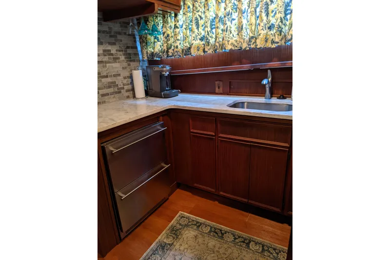 Slide: The Image of 1984 Hatteras 53 Motor Yacht kitchen with wood cabinets, stainless appliances, and floral curtains. - 26