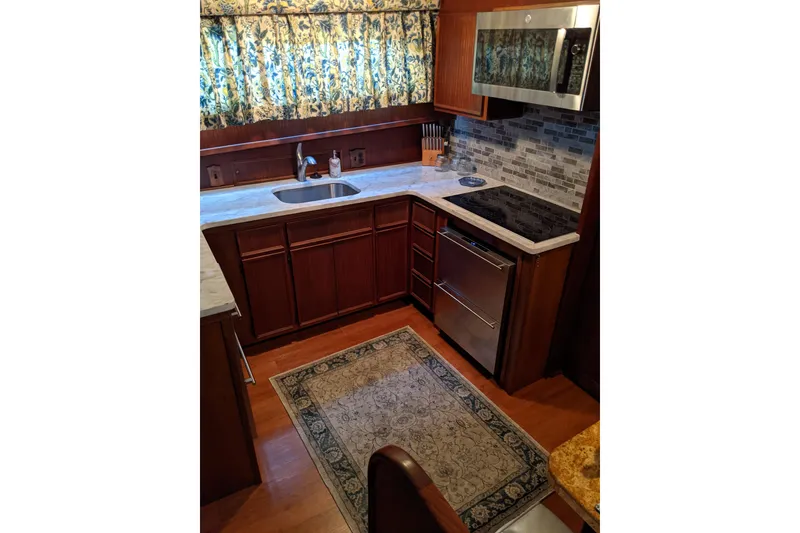 Slide: The Image of 1984 Hatteras 53 Motor Yacht kitchen with wood cabinets, marble countertops, and modern appliances. - 27