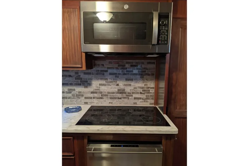 Slide: The Image of Modern kitchen with stainless steel microwave, electric cooktop, and tiled backsplash on a yacht. - 44