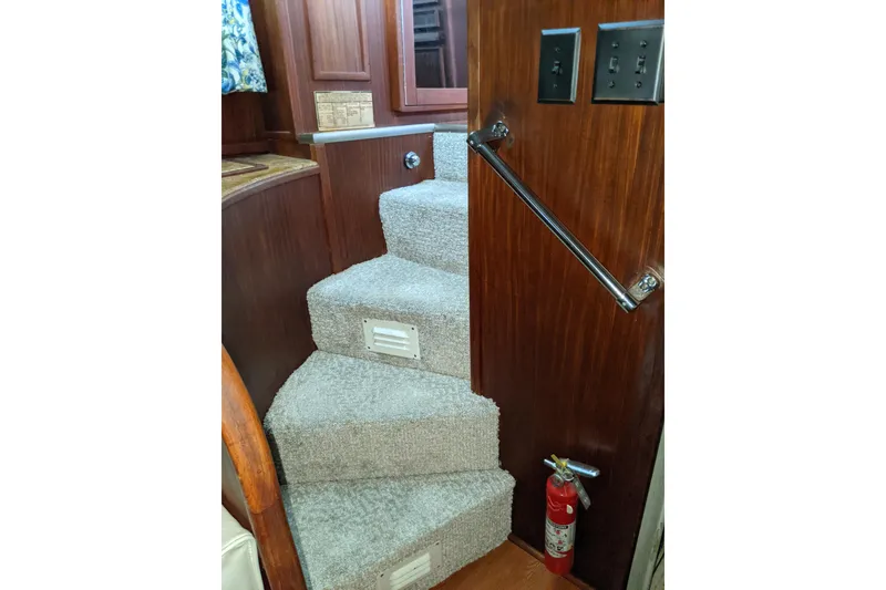 Slide: The Image of Carpeted stairs inside 1984 Hatteras 53 Motor Yacht with wooden paneling and fire extinguisher. - 8