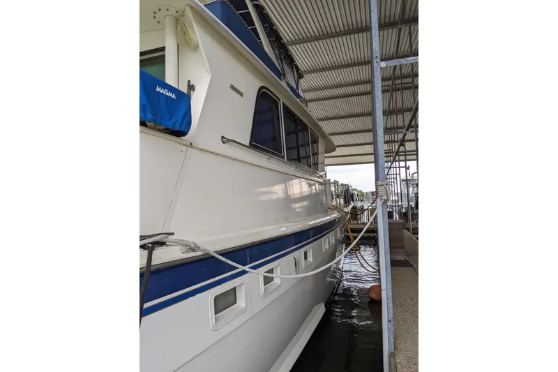 Slide: The Image of 1984 Hatteras 53 Extended Deckhouse Motor Yacht docked under a covered marina. - 87
