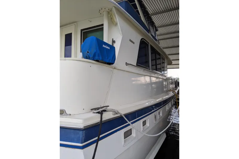 Slide: The Image of 1984 Hatteras 53 Extended Deckhouse Motor Yacht docked under a covered marina. - 88