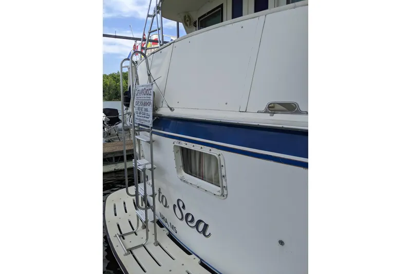 Slide: The Image of 1984 Hatteras 53 Extended Deckhouse Motor Yacht docked, featuring a ladder and window. - 89