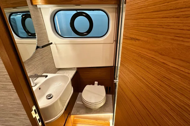Slide: The Image of 2026 Tiara Yachts 39 LS bathroom with modern sink, toilet, and porthole window. - 43