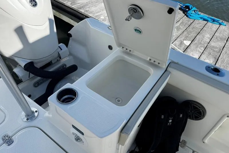 Slide: The Image of Open storage compartment on 2026 World Cat 235 TE boat, featuring cup holder and dock view. - 15