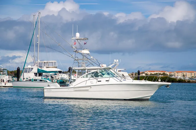Slide: The Image of 2001 Rampage 38 Express yacht anchored in a marina under a cloudy sky. - 1