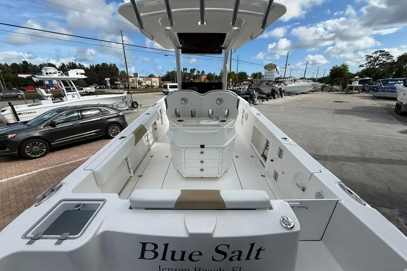 Slide: The Image of 2018 Edgewater 262CC boat, spacious deck, parked at marina, clear sky background. - 10