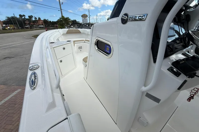 Slide: The Image of 2018 Edgewater 262CC boat interior with console and seating, parked outdoors. - 22