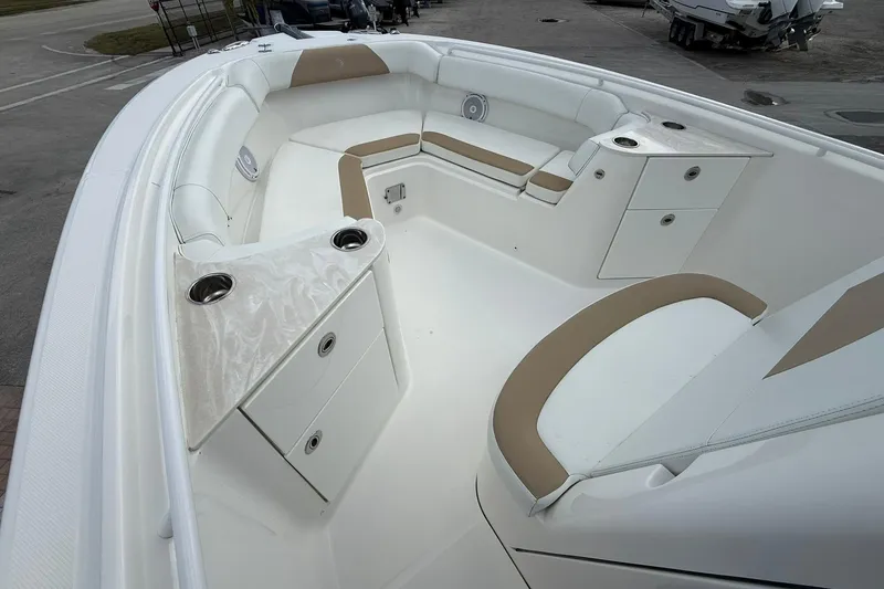 Slide: The Image of 2018 Edgewater 262CC boat interior with white and tan seating, cup holders, and storage compartments. - 26