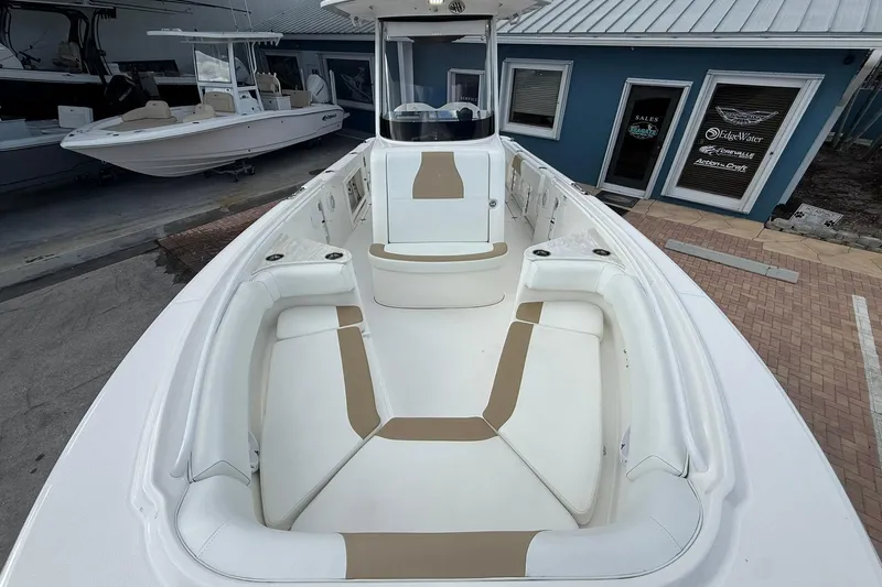 Slide: The Image of 2018 Edgewater 262CC boat interior with white and tan seating, docked near sales office. - 30