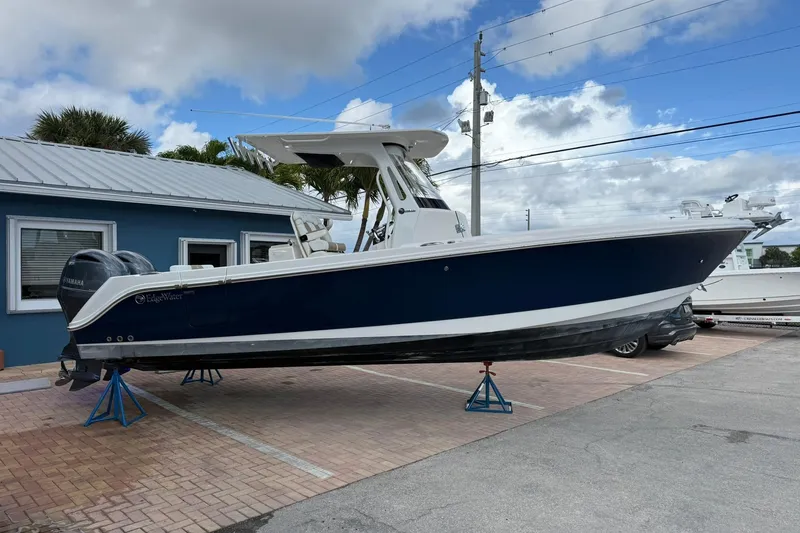 Slide: The Image of 2018 Edgewater 262CC boat on display, blue hull, parked on a brick surface. - 5