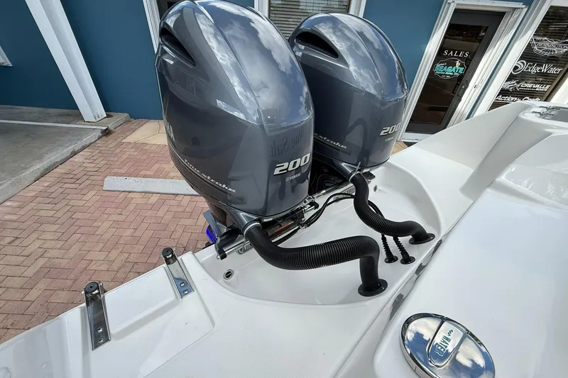 Slide: The Image of Twin Yamaha 200 engines on a 2018 Edgewater 262CC boat, parked outside a sales office. - 8