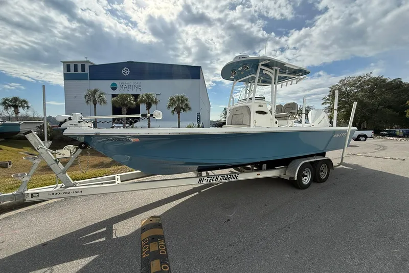 The Image of 2021 Sea Pro 248 Bay boat on trailer at marine center, under cloudy sky. - 0