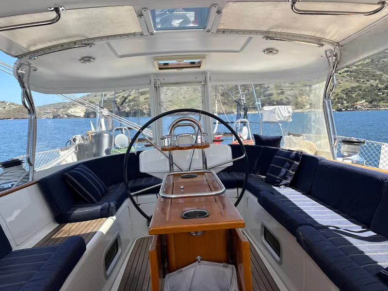 Slide: The Image of 2005 Beneteau 57 yacht cockpit with elegant seating and steering wheel, overlooking scenic waters. - 11