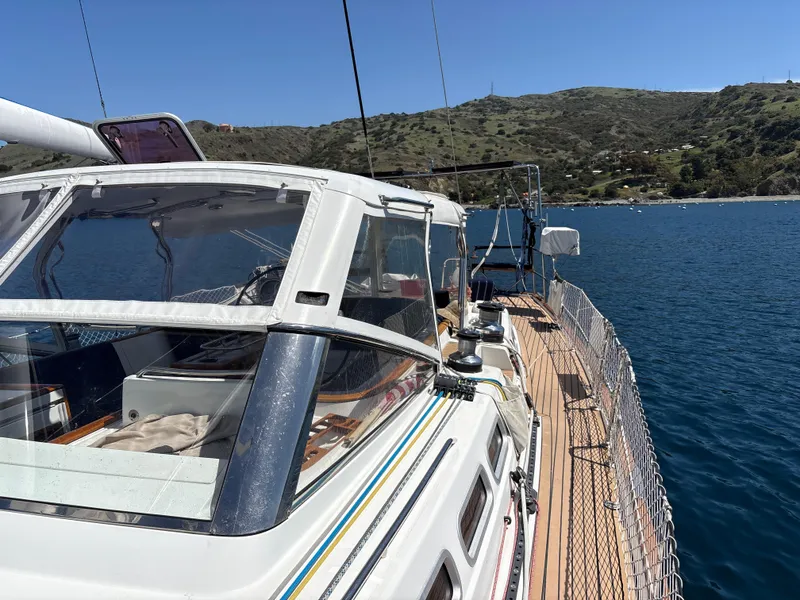 Slide: The Image of 2005 Beneteau 57 yacht on calm water, scenic coastal backdrop. - 26