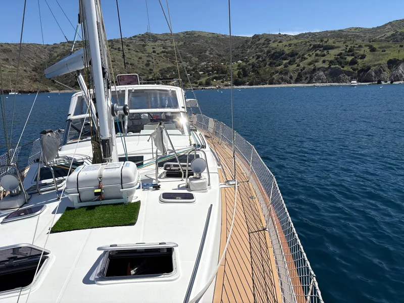 Slide: The Image of Sailing yacht Beneteau 57, 2005 model, cruising on a serene blue sea near a hilly coastline. - 27