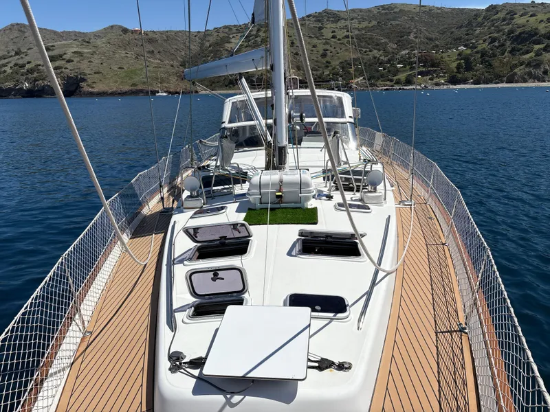 Slide: The Image of 2005 Beneteau 57 sailboat on calm water, showcasing deck and scenic background. - 28