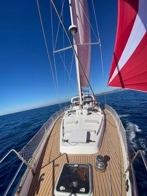 Slide: The Image of 2005 Beneteau 57 sailing on open sea with red and white sails. - 31