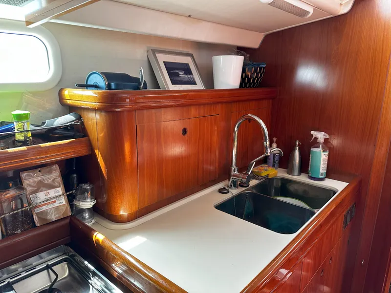 Slide: The Image of 2005 Beneteau 57 yacht kitchen with wooden cabinetry and stainless steel sink. - 44