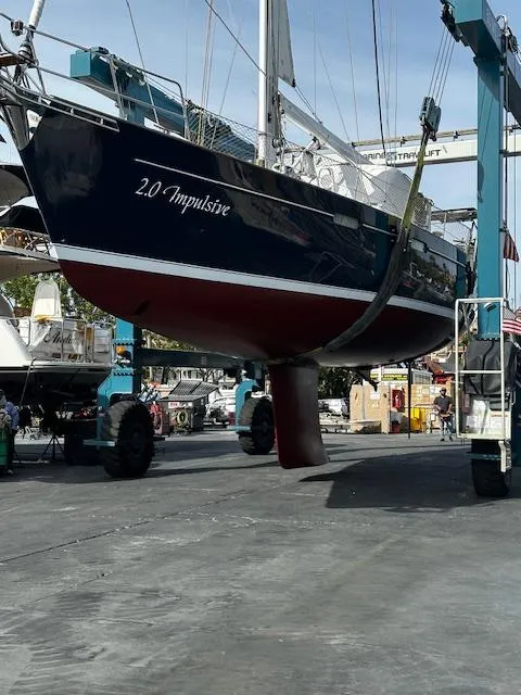 Slide: The Image of 2005 Beneteau 57 sailboat, named "2.0 Impulsive," in a boatyard lift. - 64