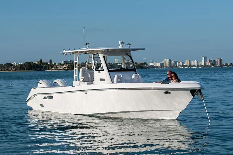Slide: The Image of Manufacturer Provided Image: 2025 Everglades 335 Center Console boat on calm water, city skyline in background. - 2