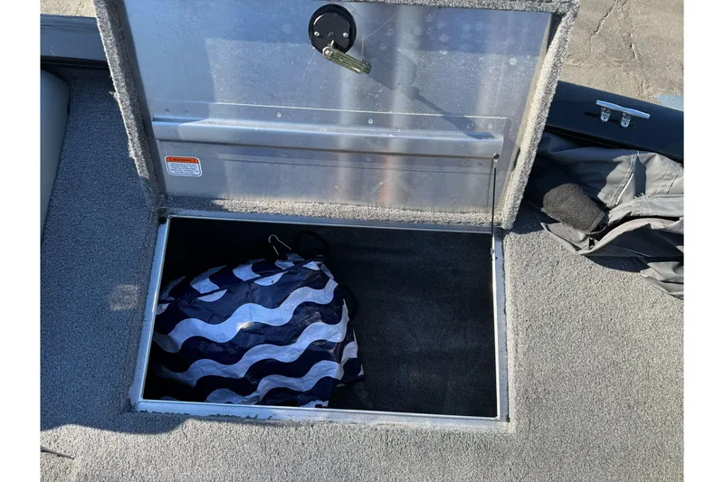 Slide: The Image of Open storage compartment on 2017 Tracker Pro Team 195 TXW boat with wavy-patterned bag inside. - 11