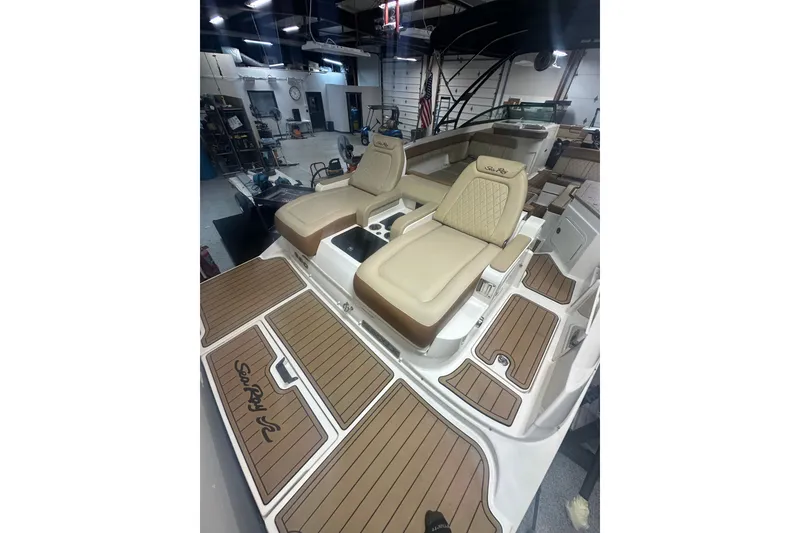 Slide: The Image of 2015 Sea Ray 290 Sundeck interior with tan seating and wood-style flooring in a showroom. - 8