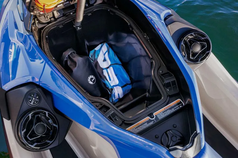 Slide: The Image of Manufacturer Provided Image: 2026 Sea-Doo Wake Pro 230 storage compartment with gear, blue exterior, and water backdrop. - 2