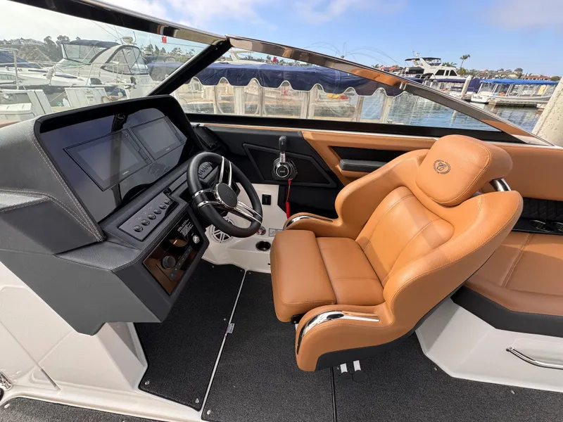 Slide: The Image of 2022 Cobalt R8 boat interior with tan leather seat and modern dashboard at marina. - 8