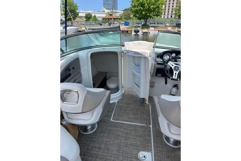 Slide: The Image of 2018 Crownline 275 SS boat interior with seating and helm, docked by the water. - 2