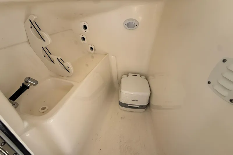 Slide: The Image of 2023 Key West 239 DFS boat interior with portable toilet and storage area. - 17