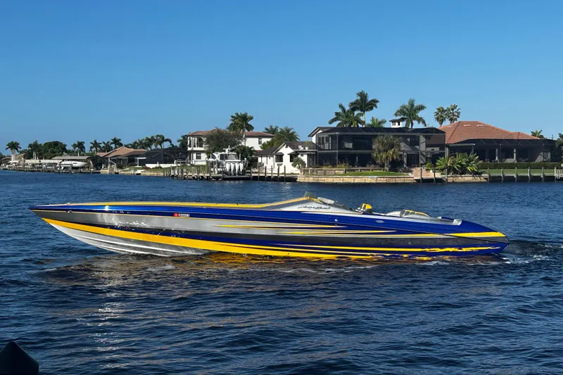 Slide: The Image of 2008 Nor-Tech 4300V speedboat on water, vibrant blue and yellow design, coastal homes in background. - 2
