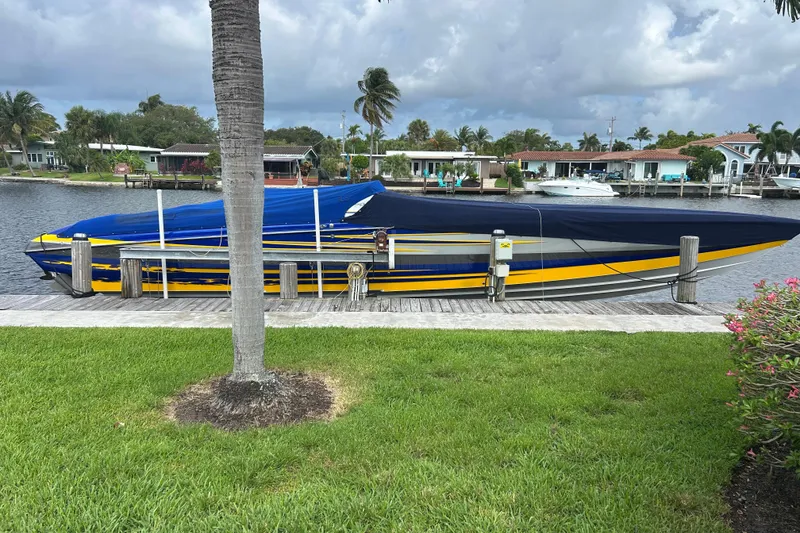 Slide: The Image of 2008 Nor-Tech 4300V boat docked, covered in blue and yellow, with waterfront homes in the background. - 7
